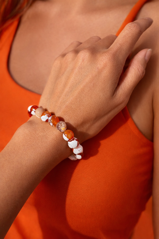 Close-up of a hand wearing a beaded bracelet on an orange background