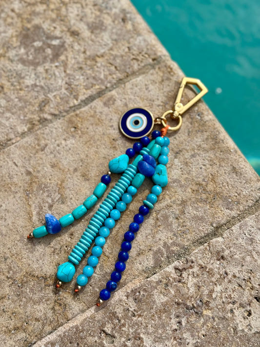 Handmade Turquoise & Evil Eye Beaded Keychain Charm – Boho Protection Keychain Gift

Add a pop of color and positivity to your everyday essentials with this handmade turquoise beaded keychain charm. Featuring a gold-tone clasp and the iconic blue evil eye charm for protection and good energy, this accessory combines beauty and meaning. The design includes a mix of turquoise, lapis, and aqua-toned beads that create a stunning coastal-inspired look.

Perfect for attaching to your keys, handbag, or backpack, t