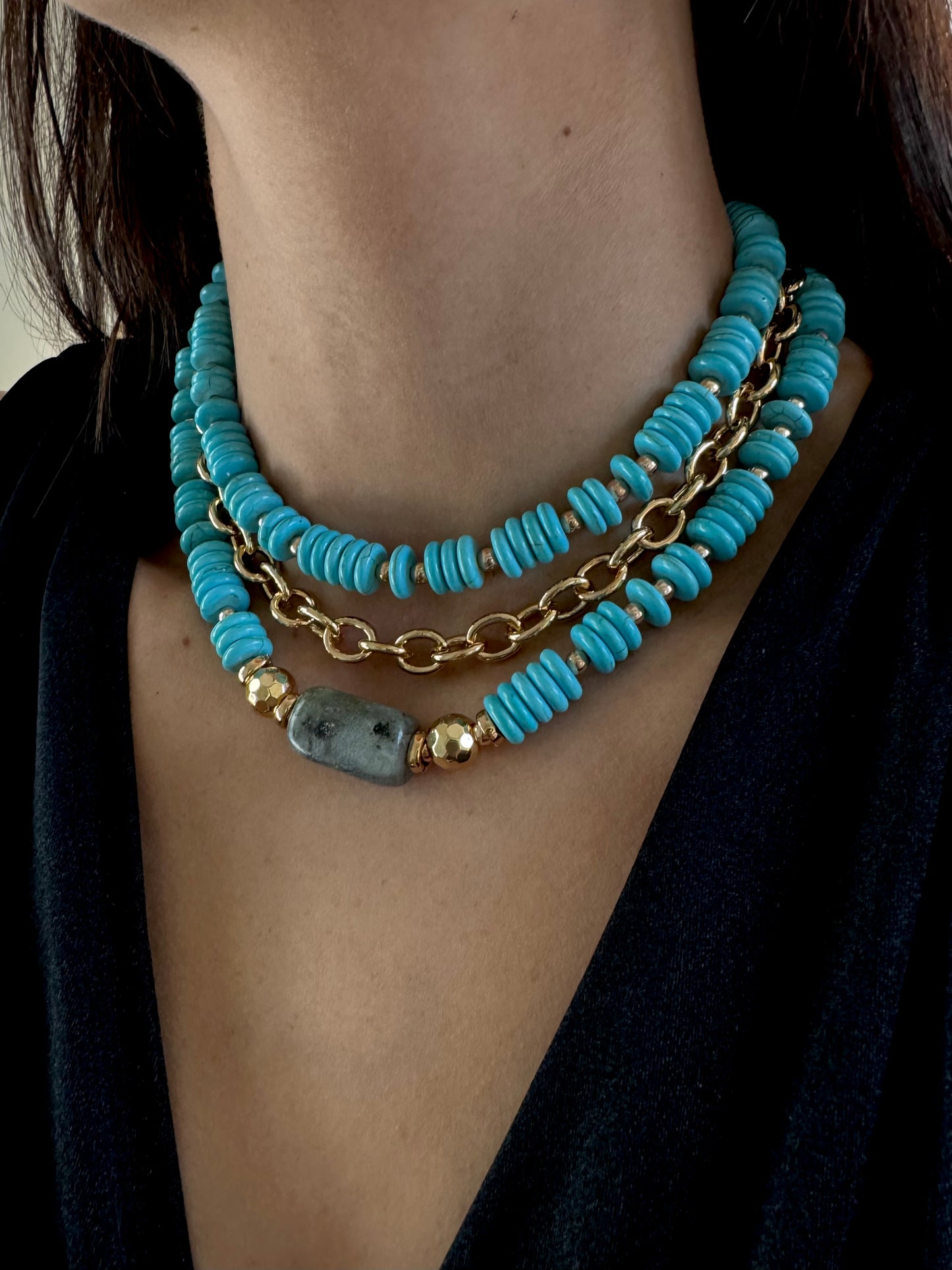 Turquoise beaded necklace with gold chain on a person wearing a black top.