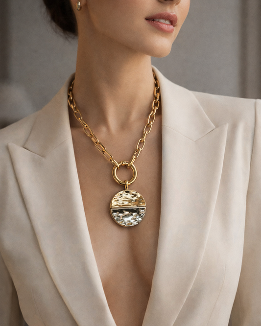 Woman wearing a gold necklace with a large pendant in a neutral setting