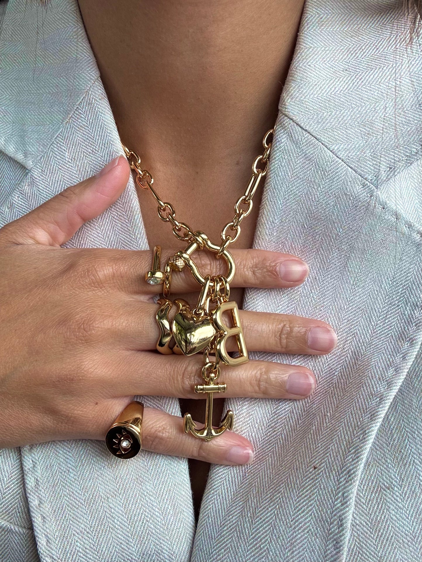 Gold necklace with charms worn by a person against a light background
