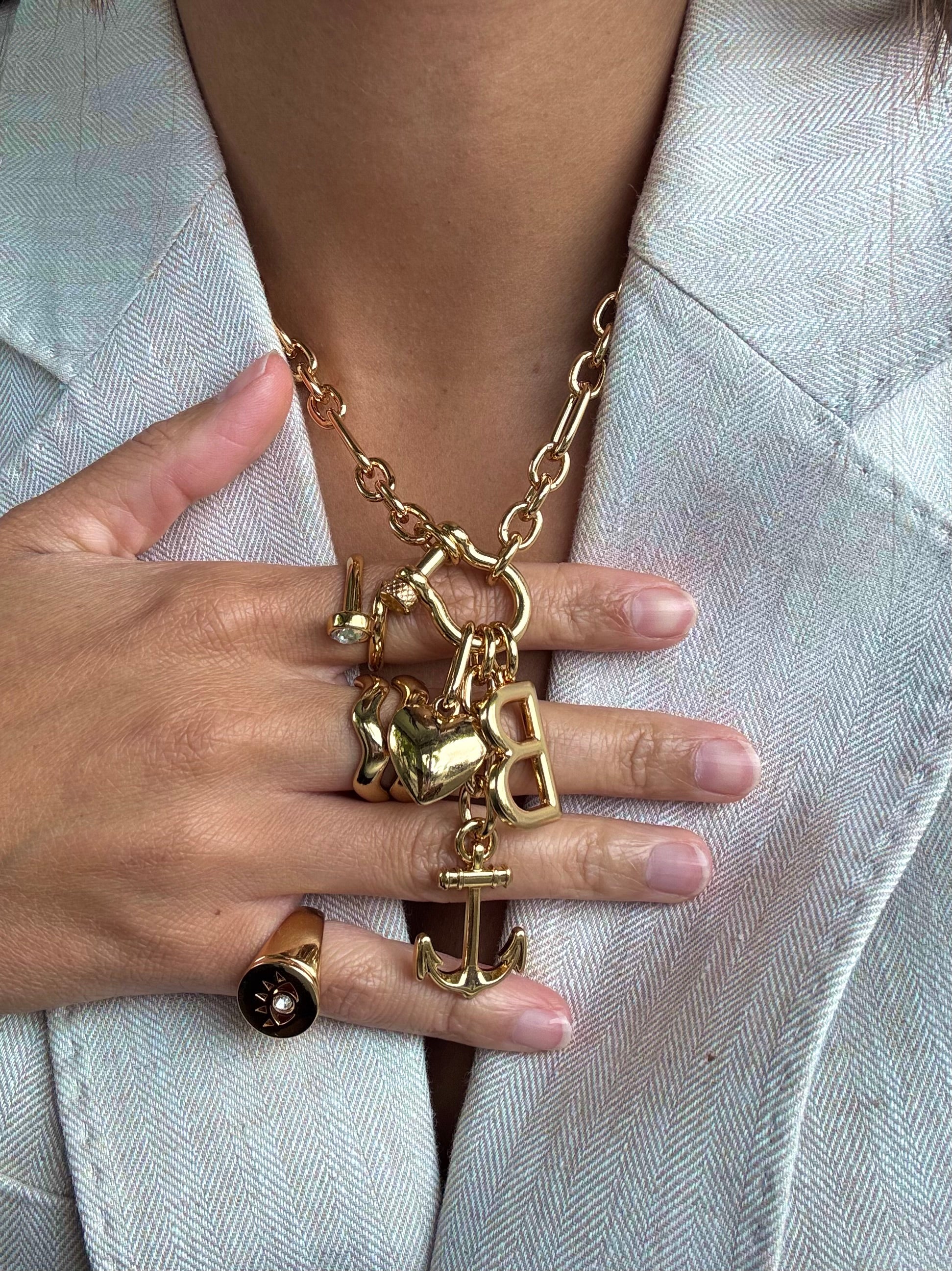 Gold necklace with charms worn by a person against a light background
