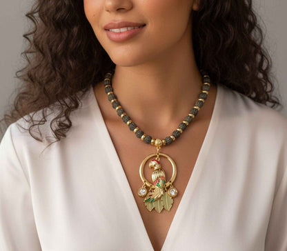 Woman wearing a gold necklace with a large pendant against a neutral background