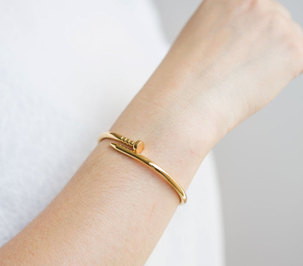 Gold bracelet on a wrist against a white background